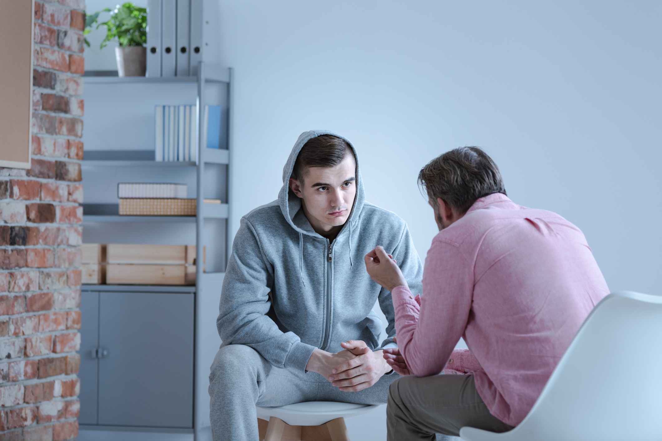 A therapist explaining an action plan for recovery to a troubled young man during an outpatient rehab session.
